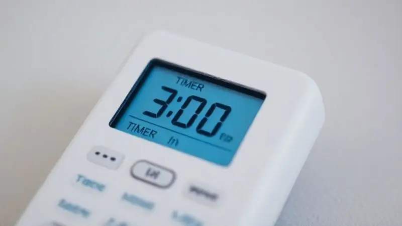Close no display digital de um controle remoto de ar-condicionado exibindo claramente o ícone de relógio da função Timer ativada.