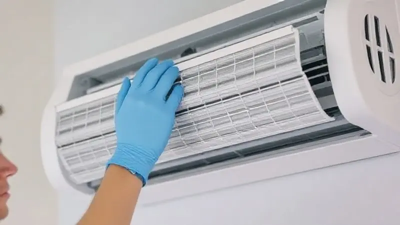 Técnico especialista realizando a limpeza do filtro de um ar-condicionado Split, um passo essencial para a manutenção e bom funcionamento.